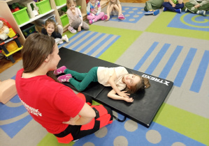 Ratowniczka pokazuje jak wygląda pozycja bezpieczna u osoby poszkodowanej.