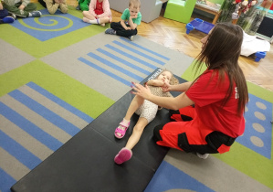 Ratowniczka układa dziewczynkę do pozycji bezpiecznej.