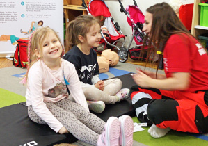 Jedna z dziewczynek pokazuje gdzie ma mieć naklejony plaster.