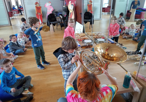 Troje dzieci gra mini koncert dla swoich kolegów i koleżanek.