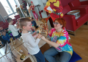 Chłopiec ćwiczy granie na waltorni.