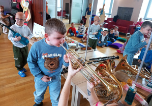 Chłopiec gra na waltorni a jego towarzysze na innych instrumentach.