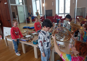 Jeden chłopiec gra na waltorni a drugi poszukuje instrumentu dla siebie.