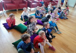 Dzieci siedzą zafascynowane dźwiękami instrumentów.