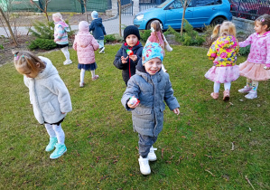 Chłopcy niosą jajka do koszyczka. Inne dzieci rozglądają się za słodkimi jajkami.