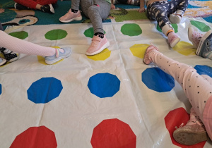 Dzieci stawiają stopy na kolorowych kropkach w grze Twister.