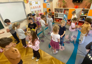 Dzieci z trzeciej grupy podczas zabawy witają się ze sobą okazując miłe gesty.