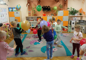 Starszaki bawią się kolorowymi balonami i świętują dzień przedszkolaka.