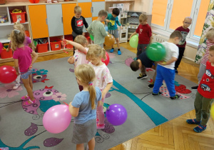 Dzieci z grupy trzeciej -"Małpek" przekładają swoje balony za plecami.