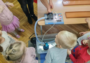 Prowadzący z pomocą dzieci uruchamia mini elektrownię wodną