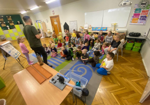 Dzieci w skupieniu słuchają mężczyznę prowadzącego zajęcia